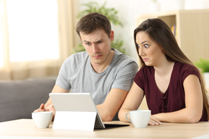 Couple reading iPad looking confused